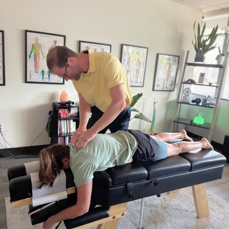 Dr. Sean Olenek doing applied kinesiology on patient’s back